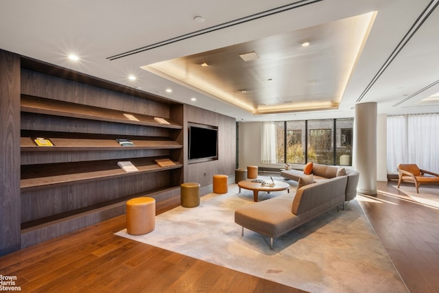 living room featuring hardwood / wood-style flooring and a tray ceiling