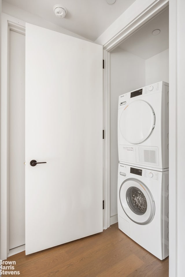 laundry room featuring laundry area, stacked washer / dryer, and wood finished floors