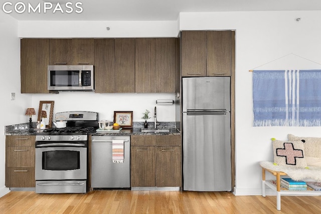 kitchen featuring dark brown cabinets, appliances with stainless steel finishes, sink, and light hardwood / wood-style floors