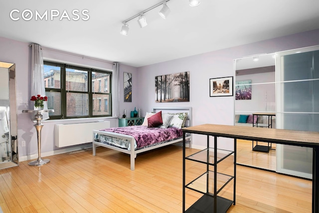 bedroom featuring radiator, baseboards, and wood-type flooring