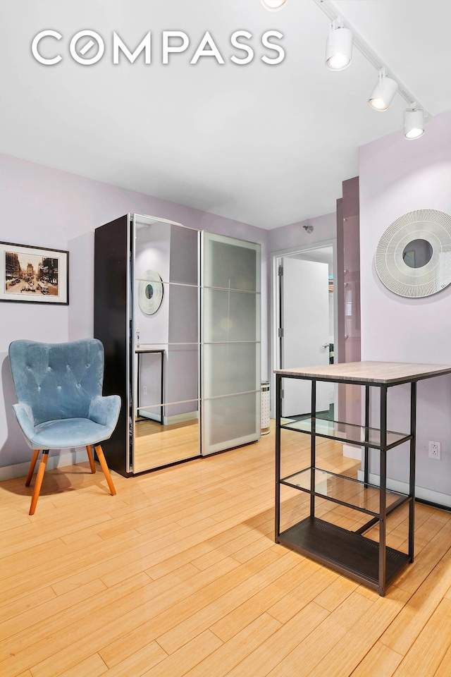 interior space with baseboards, light wood-style flooring, and rail lighting