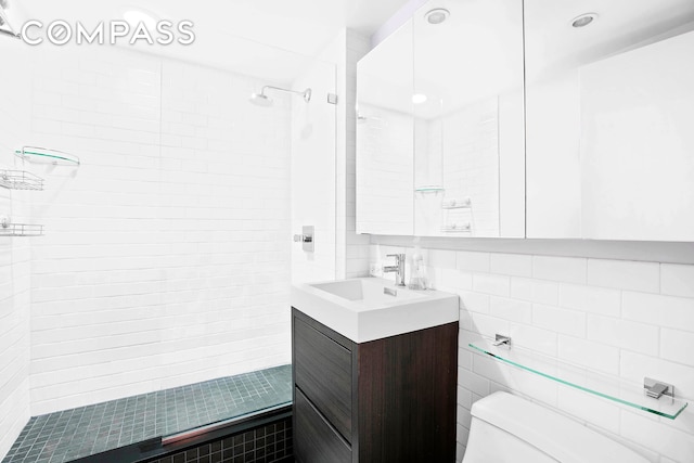 bathroom featuring backsplash, tile walls, toilet, a tile shower, and vanity