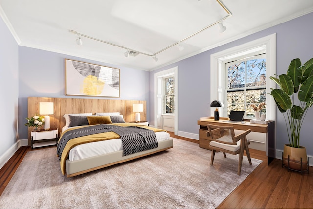 bedroom featuring ornamental molding, multiple windows, hardwood / wood-style flooring, and track lighting