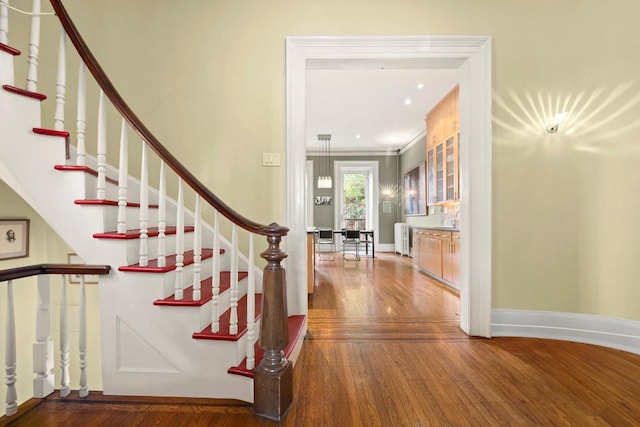 staircase featuring crown molding, hardwood / wood-style floors, and sink