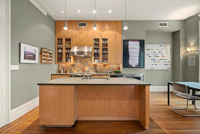 kitchen featuring pendant lighting, dark hardwood / wood-style flooring, extractor fan, and an island with sink