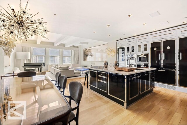 kitchen featuring light wood finished floors, a sink, freestanding refrigerator, and dark cabinets