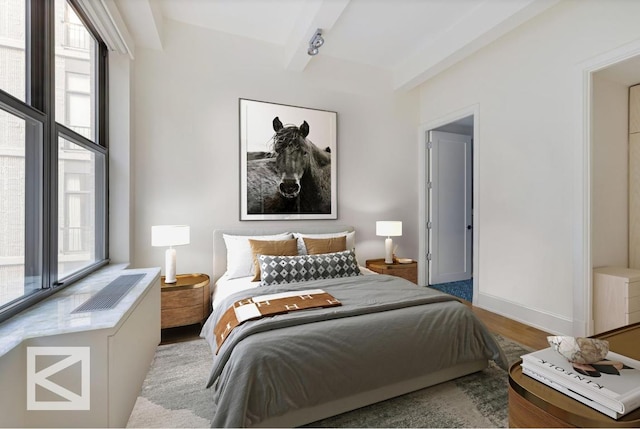 bedroom featuring light wood-type flooring and beamed ceiling