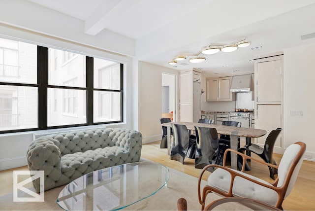 living area featuring beamed ceiling, baseboards, and light wood-style floors