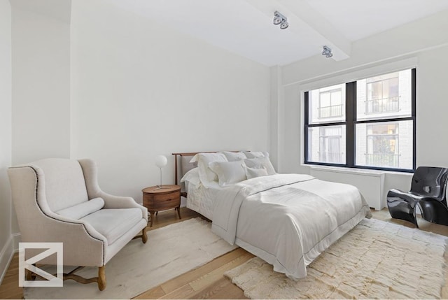 bedroom with light wood-type flooring and beamed ceiling