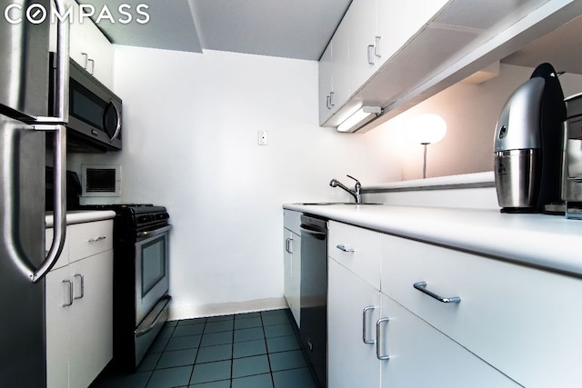 kitchen with dark tile patterned floors, appliances with stainless steel finishes, sink, and white cabinetry