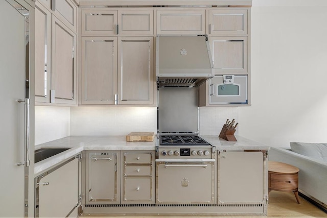 kitchen featuring backsplash, premium range hood, light hardwood / wood-style floors, stainless steel gas cooktop, and light stone countertops