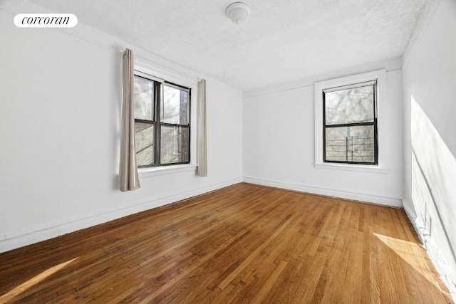 spare room with light wood-type flooring and a textured ceiling