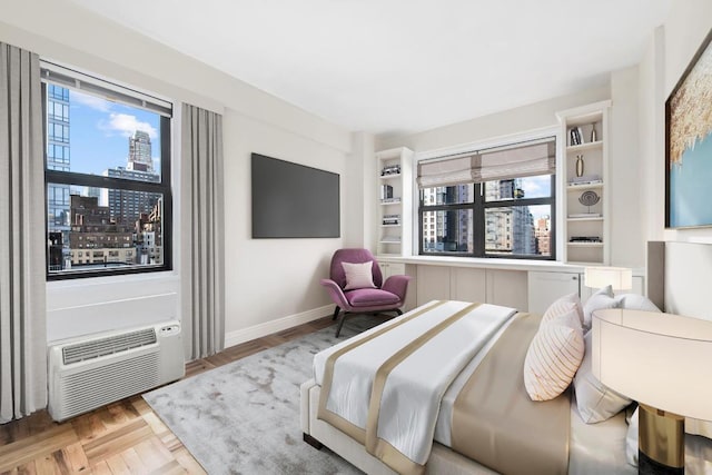 bedroom featuring multiple windows, baseboards, and a wall mounted AC