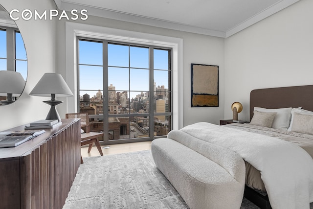 bedroom featuring crown molding, a view of city, and light wood-type flooring