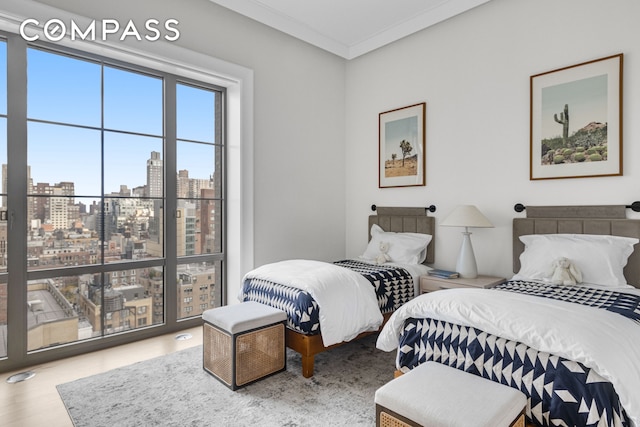 bedroom featuring crown molding, a view of city, and wood finished floors