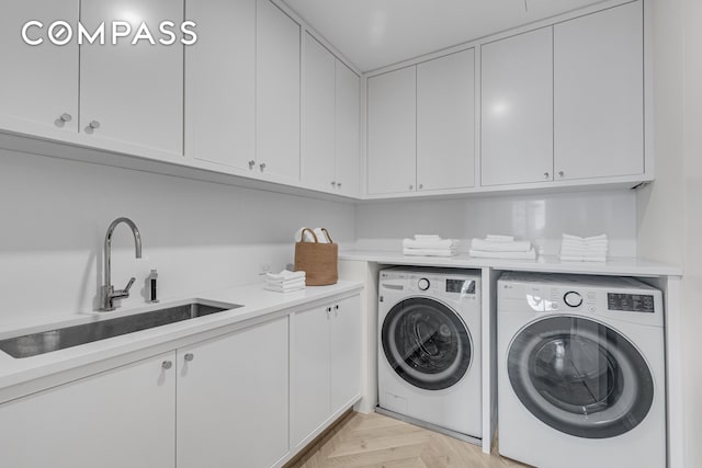 clothes washing area with a sink, cabinet space, and washer and clothes dryer