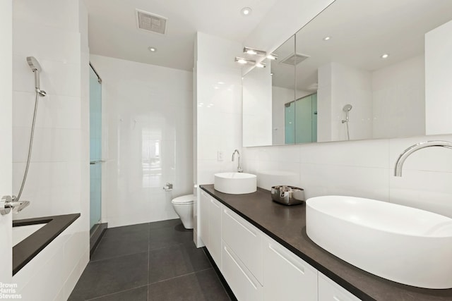 bathroom featuring a shower with shower door, tile walls, tile patterned flooring, vanity, and toilet