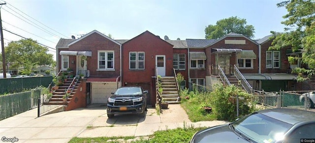 view of front of property featuring concrete driveway, an attached garage, fence, and brick siding