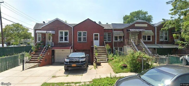 view of front of home featuring stairs, a garage, fence, and concrete driveway