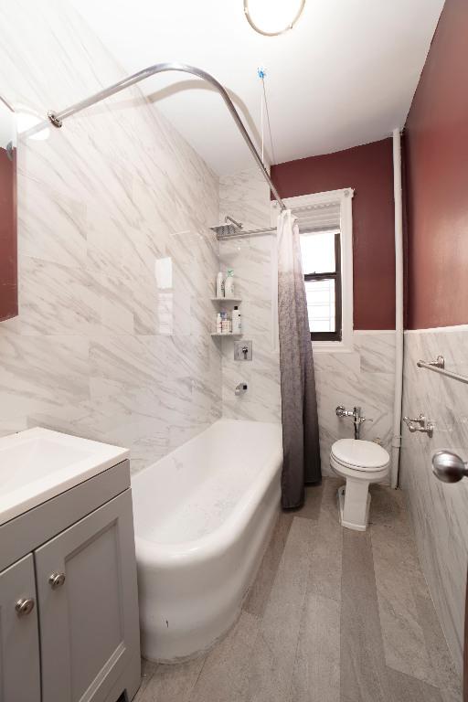 full bathroom featuring tile walls, hardwood / wood-style flooring, enclosed tub / shower combo, vanity, and toilet