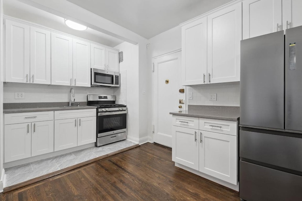 kitchen with sink, stainless steel appliances, tasteful backsplash, and white cabinetry