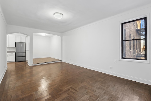 spare room featuring arched walkways and baseboards