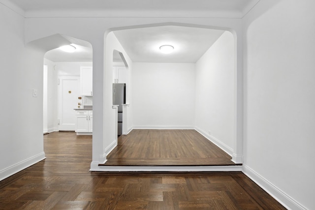interior space with baseboards and arched walkways