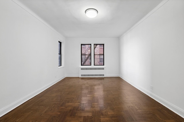 empty room featuring radiator heating unit, crown molding, and baseboards