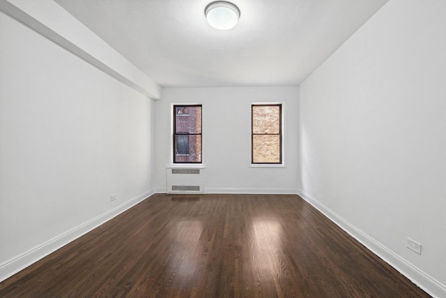 unfurnished room featuring baseboards and dark wood-type flooring