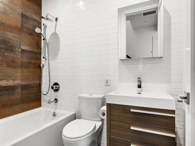 full bathroom featuring toilet, tiled shower / bath, tile walls, vanity, and backsplash