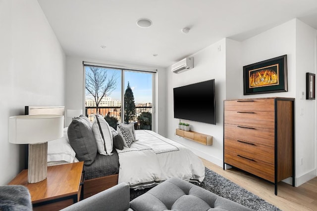 bedroom featuring a wall mounted air conditioner and light hardwood / wood-style flooring