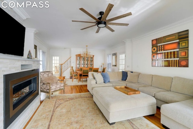 living room featuring ceiling fan with notable chandelier, ornamental molding, a healthy amount of sunlight, and light hardwood / wood-style floors