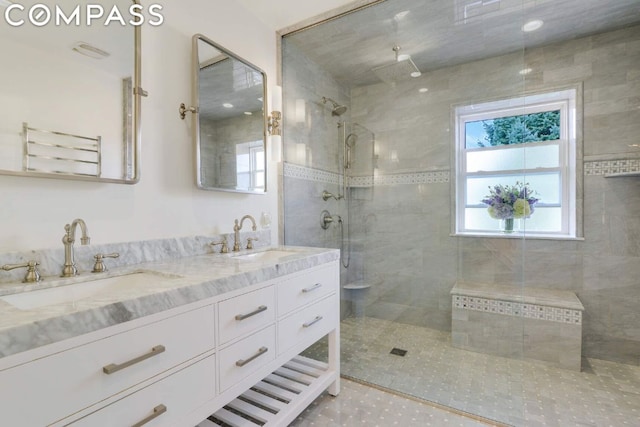 bathroom featuring tile patterned flooring, a tile shower, and vanity