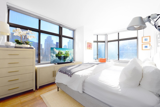 bedroom featuring light wood-type flooring and floor to ceiling windows