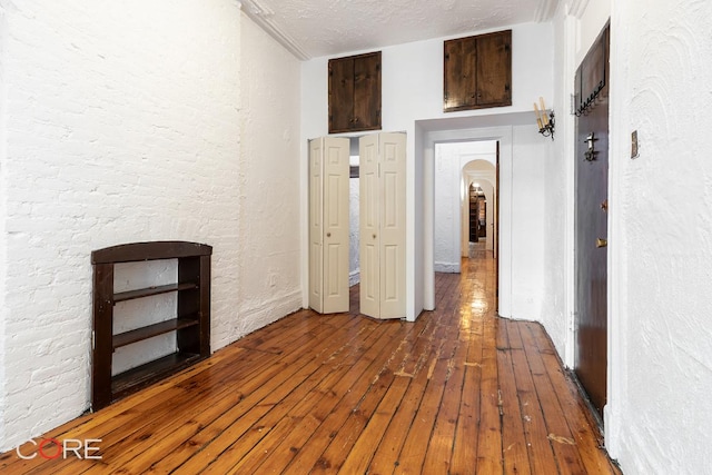 hallway with hardwood / wood-style floors and a textured ceiling