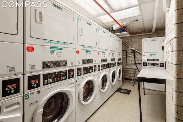 clothes washing area with stacked washing maching and dryer and washing machine and clothes dryer