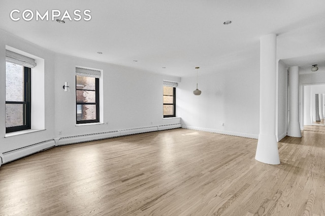 empty room with light wood-type flooring and baseboard heating