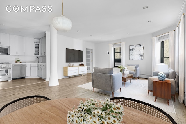 living area featuring a baseboard heating unit, light wood-type flooring, a healthy amount of sunlight, and recessed lighting