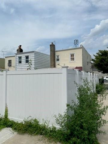 view of home's exterior featuring a chimney and fence