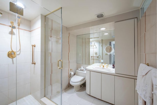 bathroom featuring tile patterned flooring, vanity, tile walls, toilet, and walk in shower