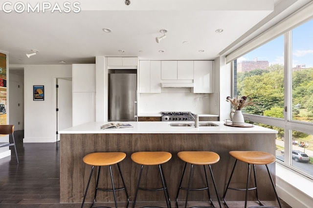 kitchen featuring sink, white cabinetry, high end fridge, a kitchen island with sink, and dark hardwood / wood-style flooring