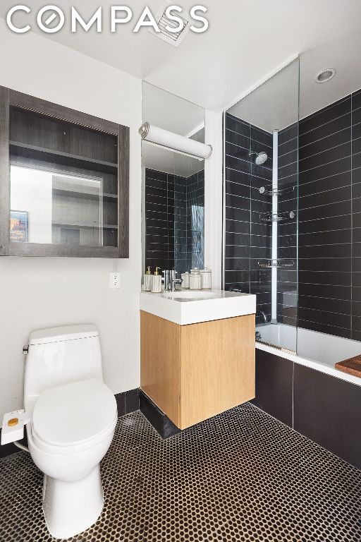 full bathroom with toilet, tiled shower / bath combo, and vanity