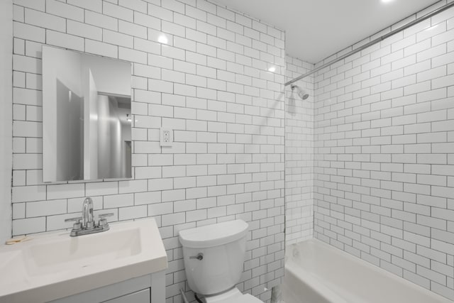 full bathroom with vanity, toilet, tiled shower / bath combo, and tile walls