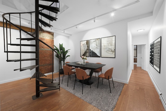 dining area with hardwood / wood-style floors, track lighting, and baseboard heating