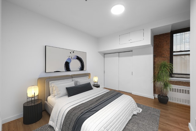 bedroom featuring radiator heating unit, a closet, and wood-type flooring