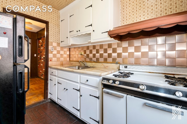 kitchen with white cabinets, black fridge with ice dispenser, white gas range, light countertops, and a sink