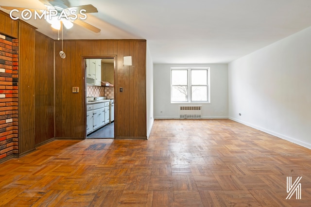 empty room featuring ceiling fan, radiator heating unit, and baseboards