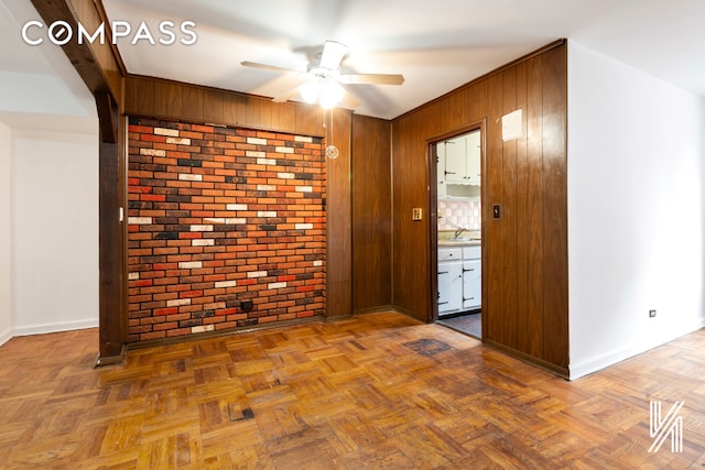 unfurnished room featuring brick wall and ceiling fan