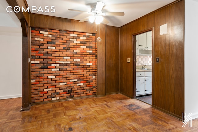 corridor with brick wall, wooden walls, baseboards, and a sink