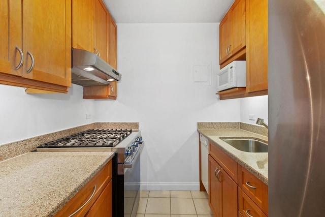 kitchen with light tile patterned floors, sink, light stone counters, and stainless steel appliances